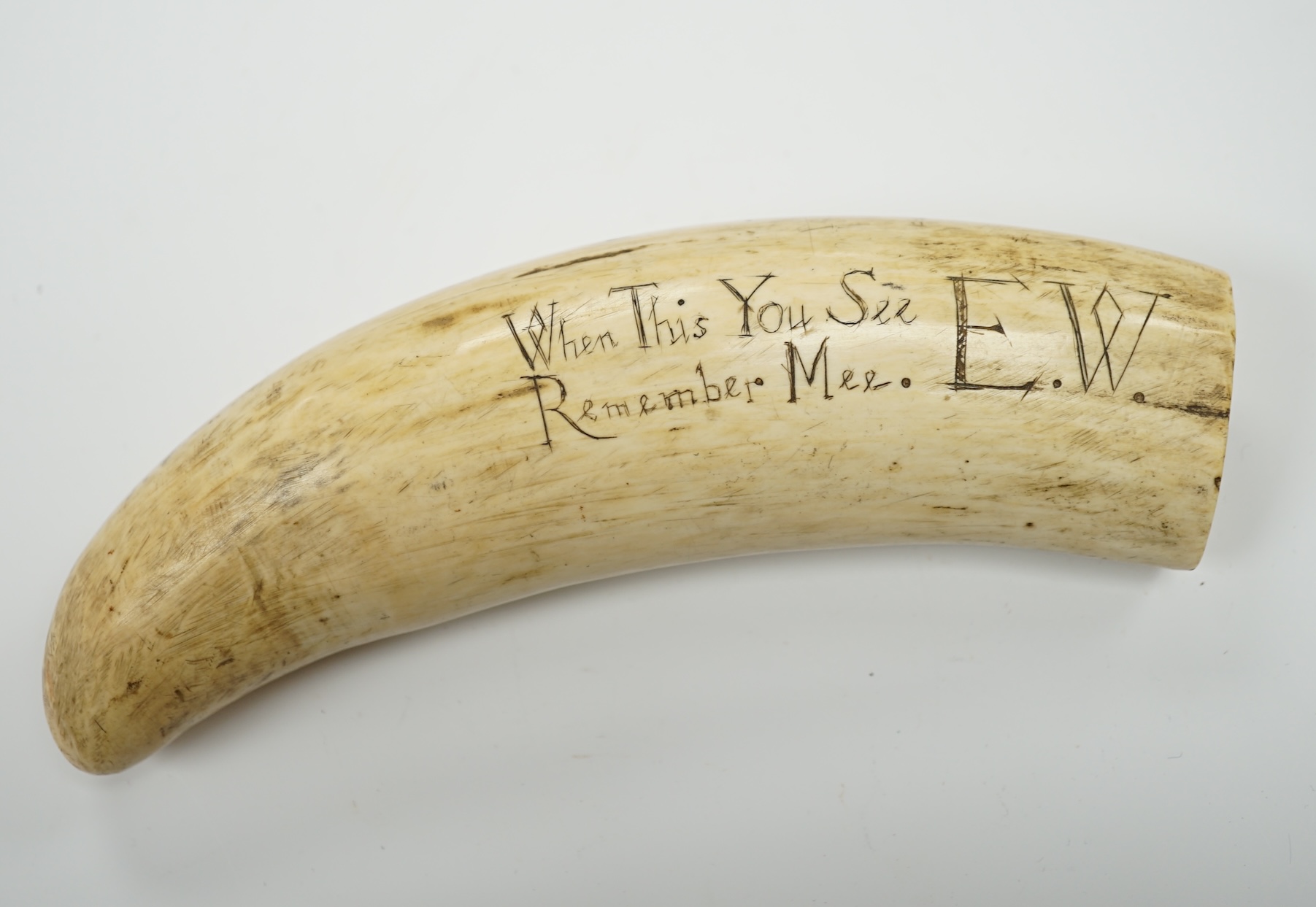 A 19th century Scrimshaw walrus tooth with carved motto ‘When this you see, remember mee’ and initialled E.W, 16cm in length